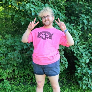 Person in rainbow loon shirt flashing peace signs